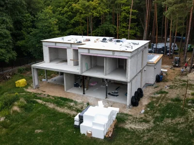 Nowoczesny dom piętrowy w stanie surowym z płaskim dachem w otoczeniu lasu – realizacja LEVEL